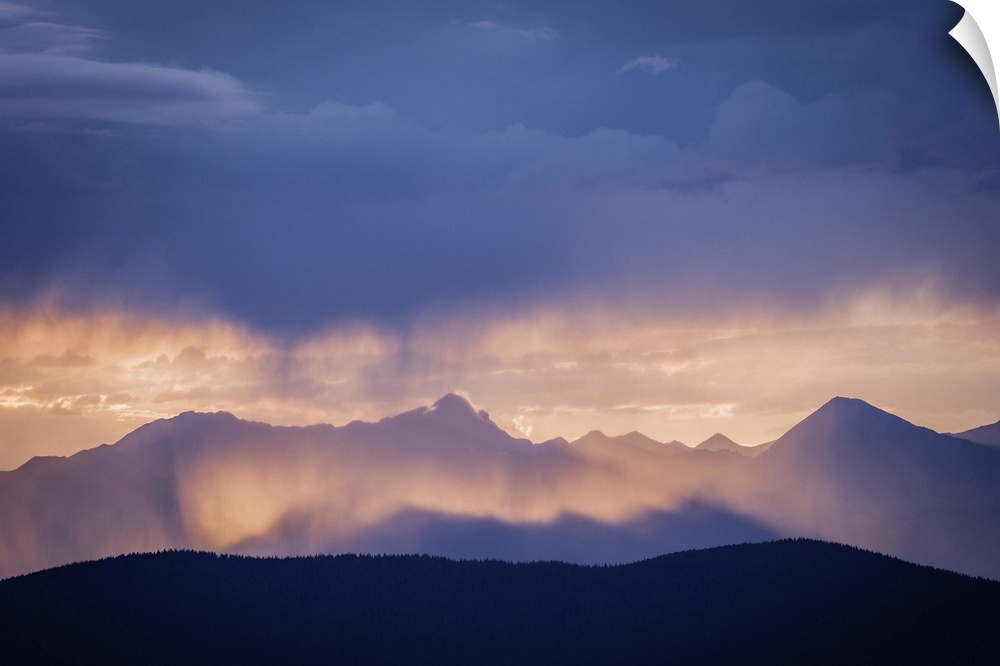 A photograph of mountains cast in shadow from the light of the setting sun.