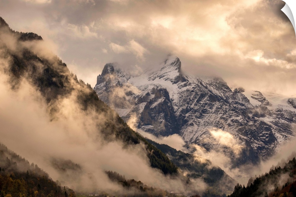 Beautiful landscape photograph of snowy mountain peaks engulfed in clouds.