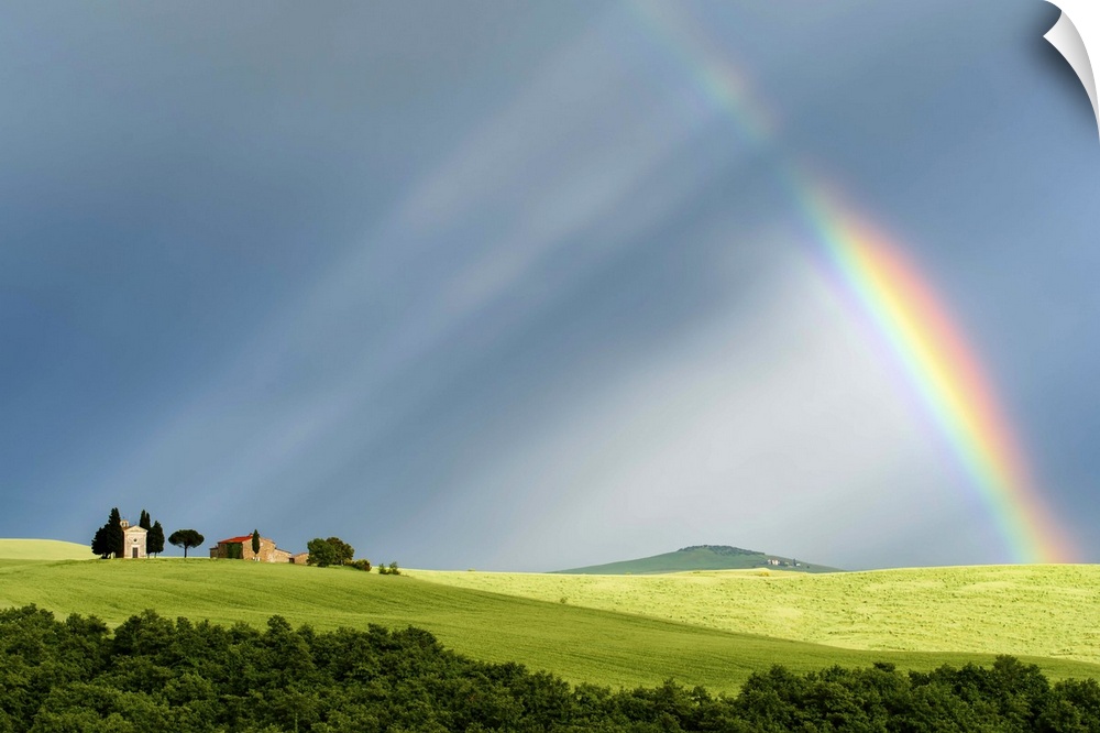 A photograph of a Tuscan countryside bathed in the light streaming from a rainbow.