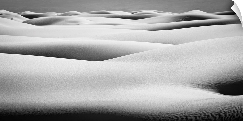 Black and white landscape photograph of contrasting hilly sand dunes.