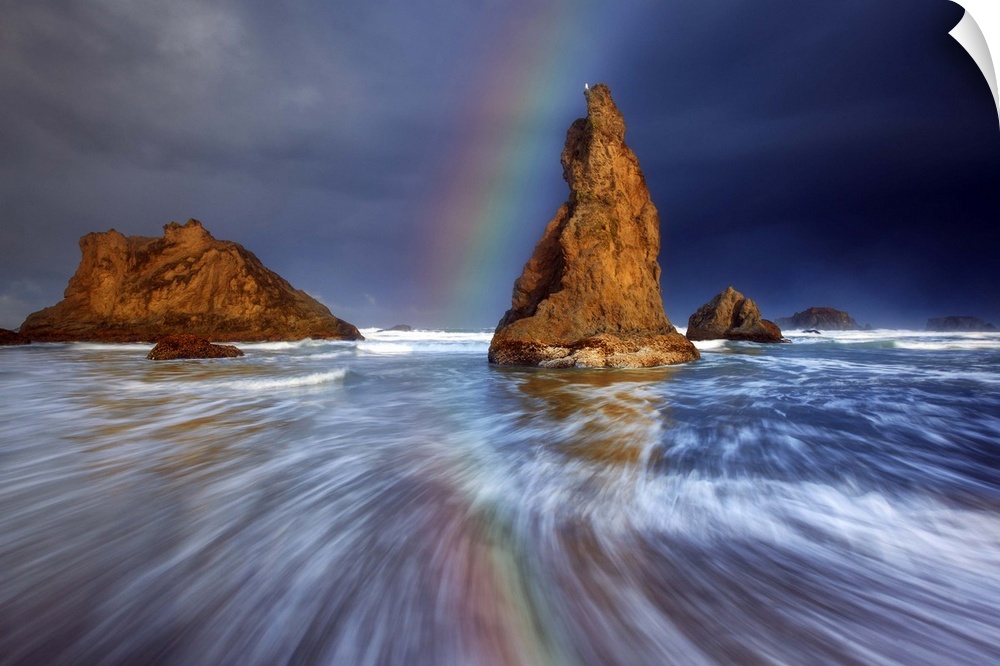 A rainbow over sea stacks in the ocean.