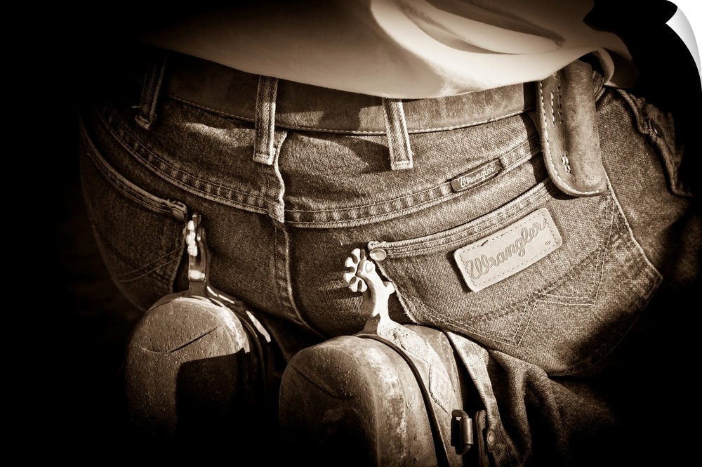 Sepia photograph of a cowboy on his knees with spurs resting on his jeans with a black vignette around the sides.