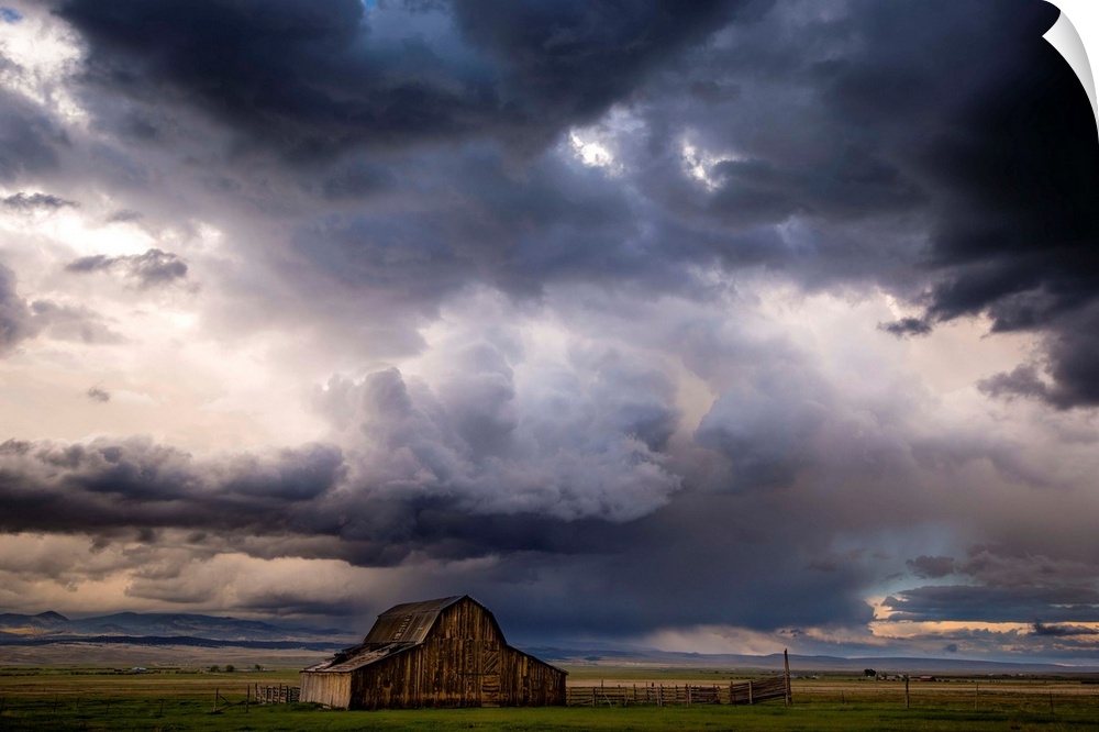 A photograph of a farm landscape under the dark clouds of an incoming storm.