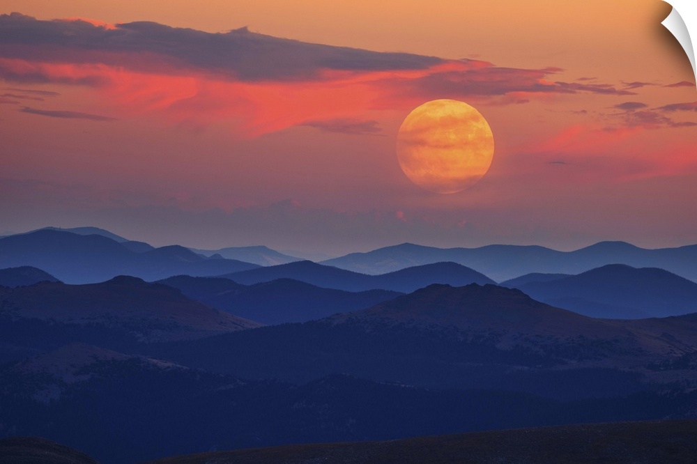 A glowing moon at dawn over misty mountains.