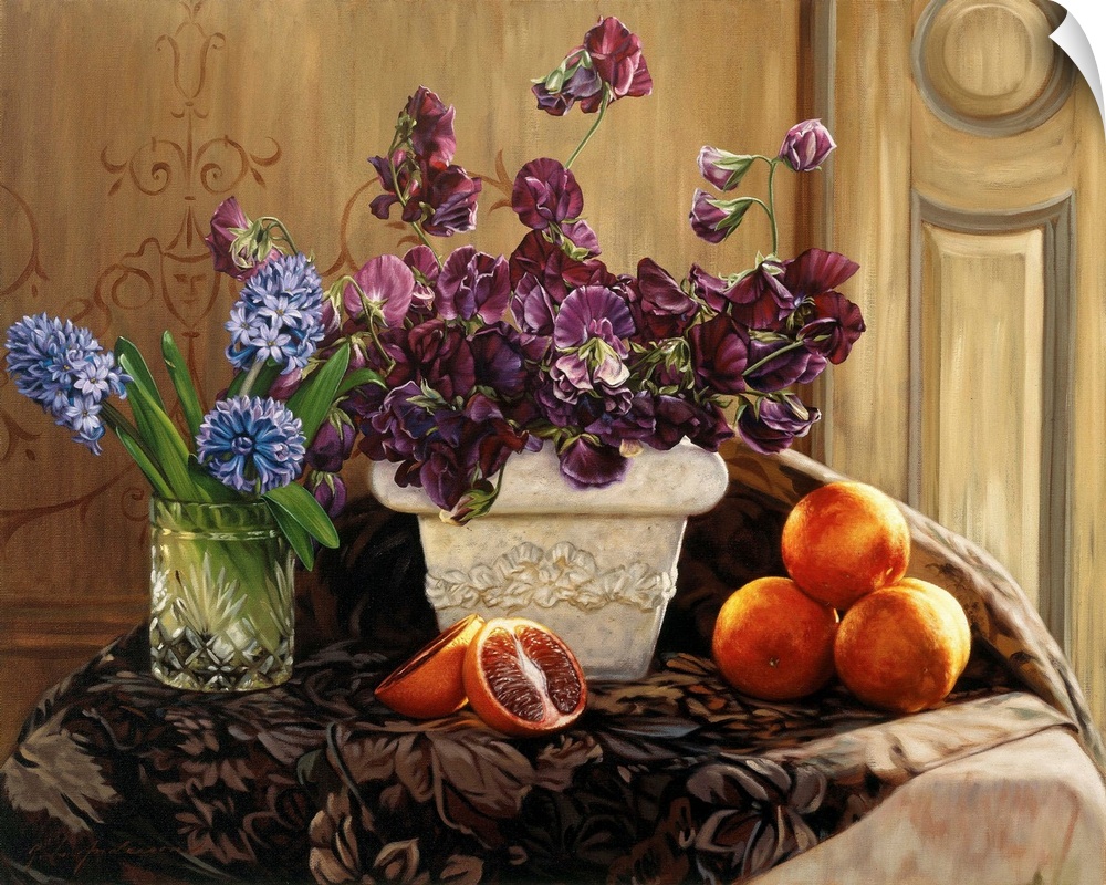 A large white vase filled with purple flowers, one clear vase filled wtih blue flowers and blood oranges on the table.