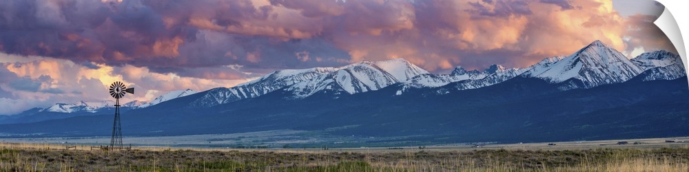 A photograph of mountain under dramatic clouds illuminated by the sunset.