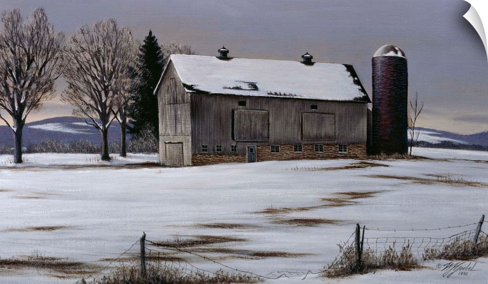 An old barn and silo in a meadow with snow on the ground.