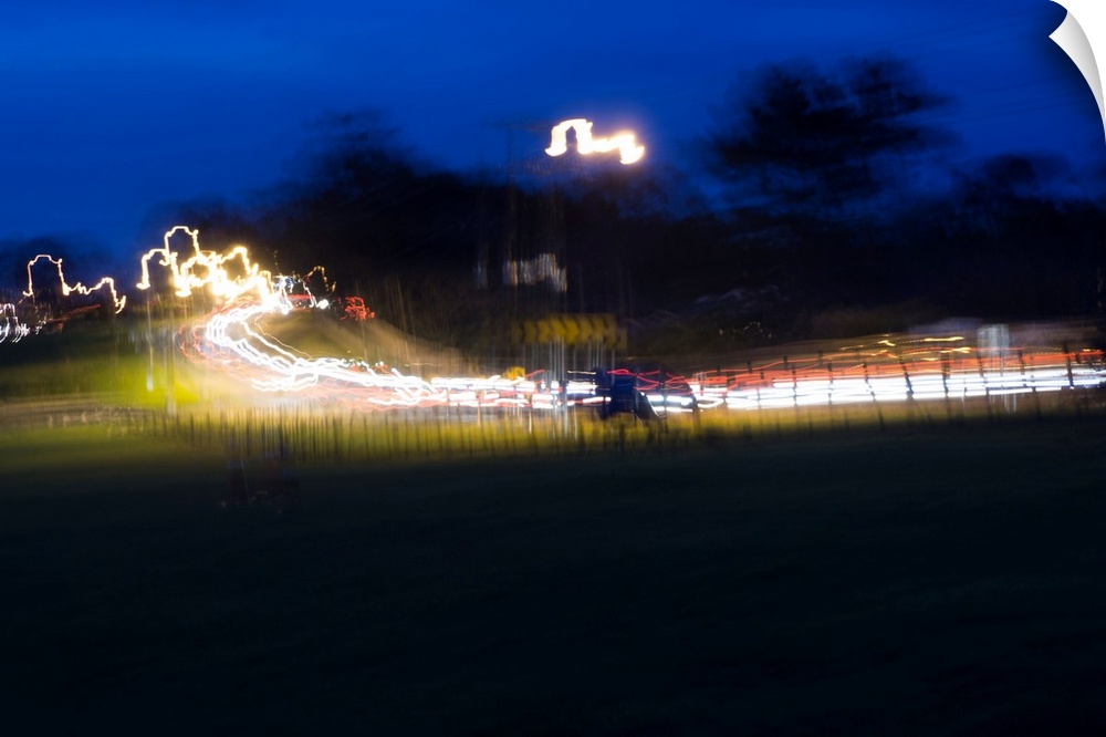 Impressionist photograph of a busy country road at night with cars light painting the road.