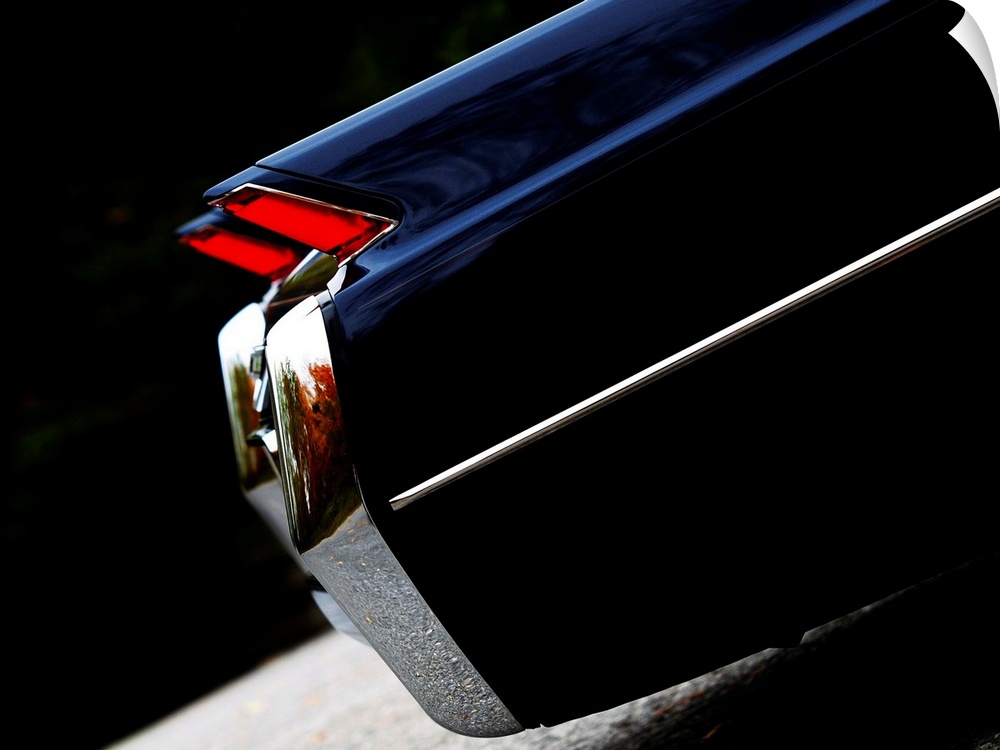 Angled photograph of the rear side of a 64 Cadillac Coupe de Ville 3 with red break lights.