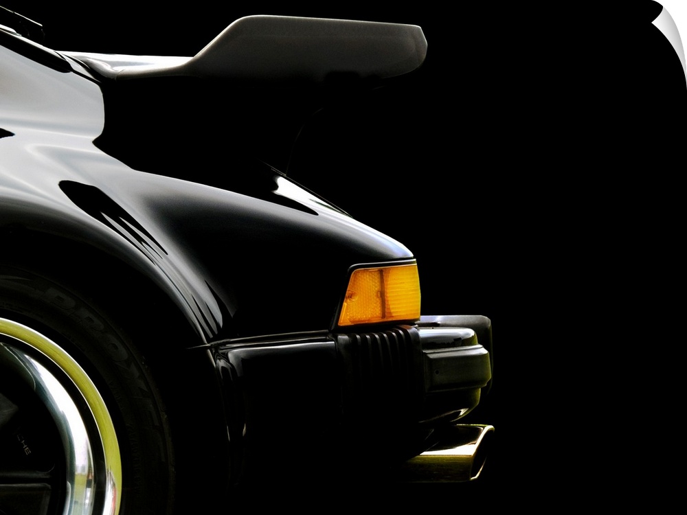 Photograph of the rear and back wing of a black 78 Porsche 930 with a solid black background.