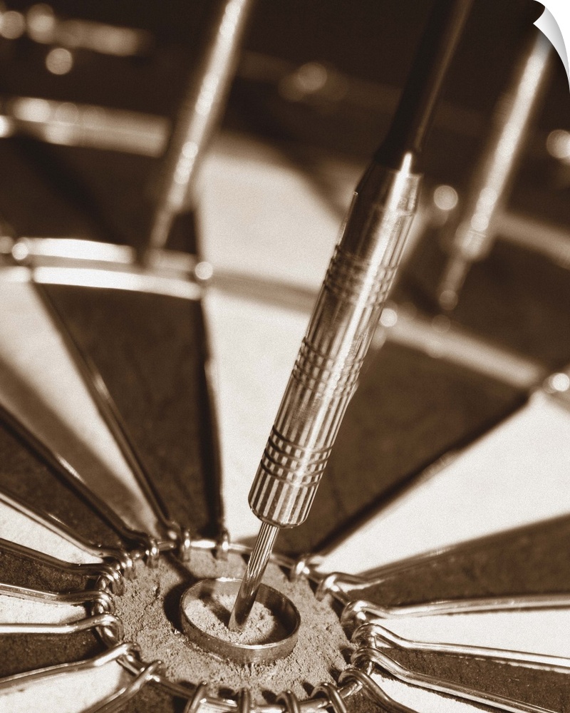 Sepia toned photo of a dart in the center of a dart board.
