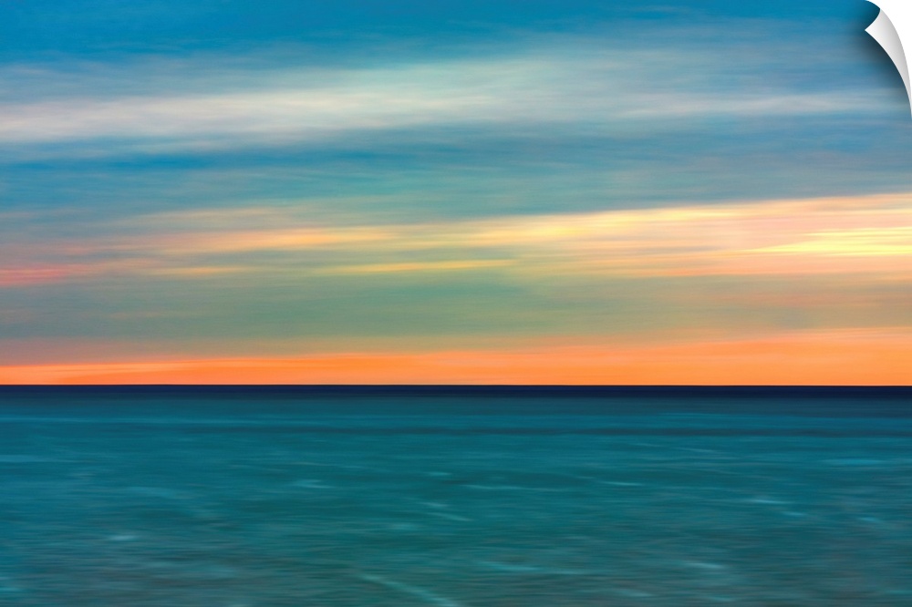 Horizontal image of a color sunset over calm ocean waters.