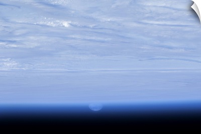 Distorted by the lens of the Earth's atmosphere, the Moon rises over a bed of clouds