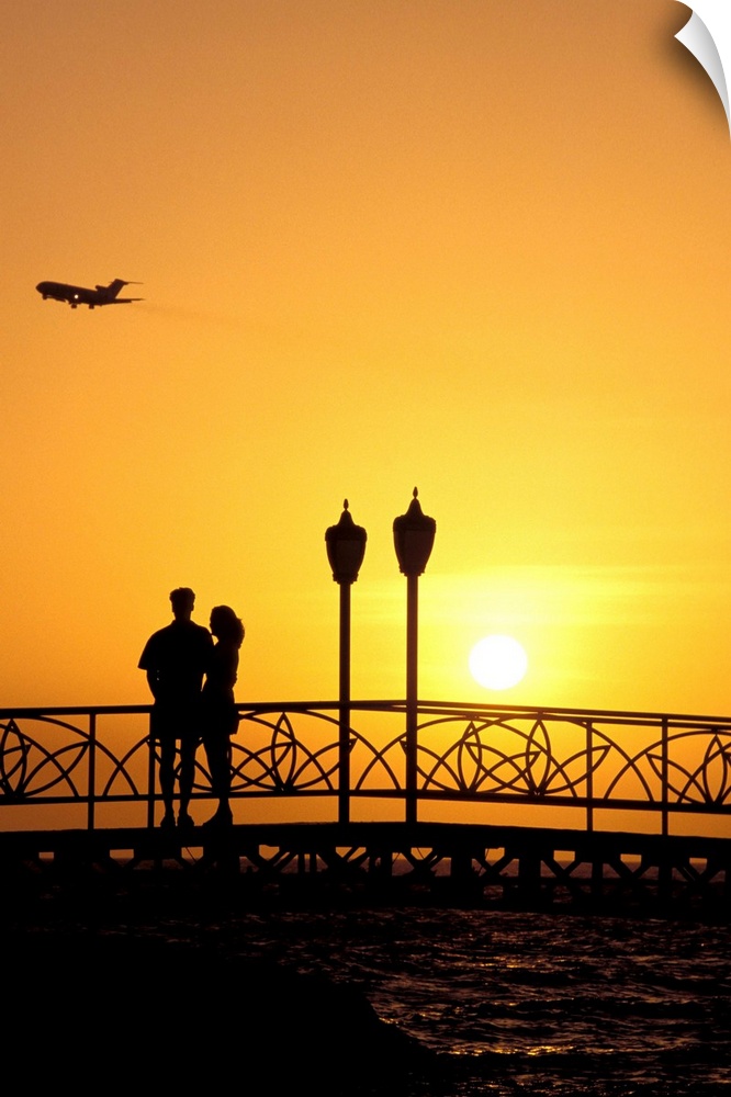Caribbean, Aruba, Oranjestad. Couple enjoying sunset with plane overhead