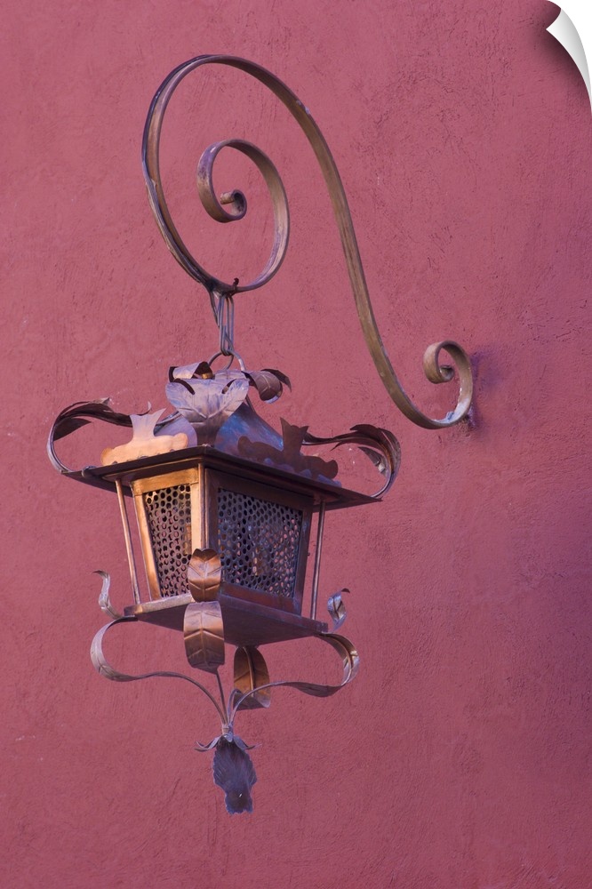Mexico, San Miguel de Allende. Ornate copper lamp hung from pink-purple wall.