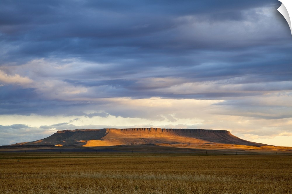 Morning sunlight breaks through the cloud cover and illuminates Square Butte near Great Falls, Montana, USA
