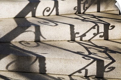Shadows of wrought iron railing on steps of historic building