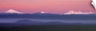 The pink blanket of sunrise warms the Oregon Cascades