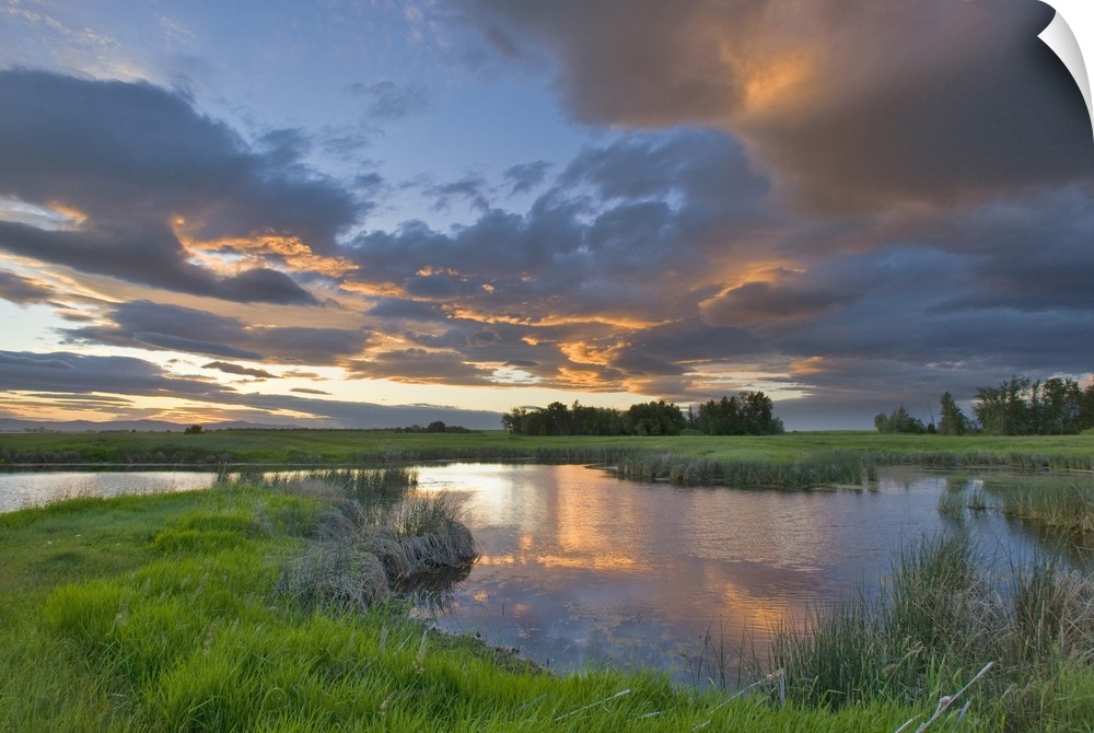 Vivid sunset clouds reflect into small pond at the Ninepipe Wildlife Management Area in the Mission Valley of Montana