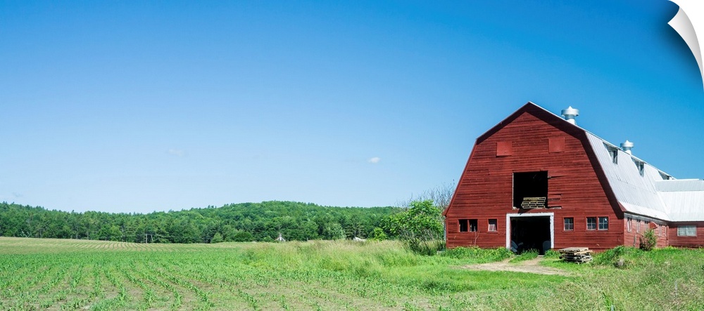 A red barn, green fields, and blue sky of a classic Vermont family farm.