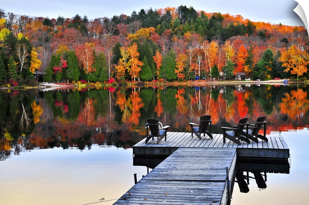 Wooden dock with chairs on calm fall lake.
