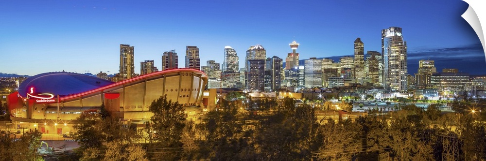 Canada, Alberta, Calgary, Skyline of downtown Calgary and Saddledome illuminated at dusk.