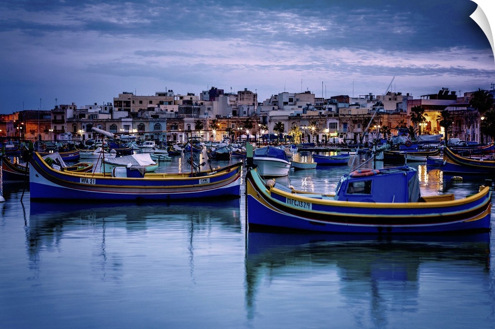 Malta, Marsaxlokk, Mediterranean sea, Luzzu, traditional fishing boats and Marsaxlokk harbor at dusk.