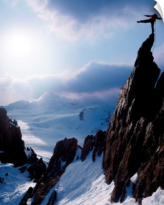 Rock climber at the peak of a snow capped mountain
