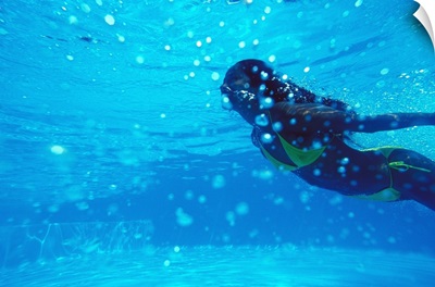 Young woman swimming underwater, in pool