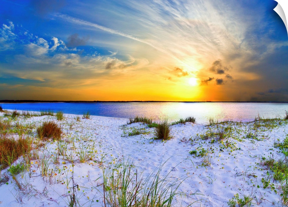 An orange sunset with sweeping clouds over a white sandy beach landscape. Landscape taken near Navarre Beach, Florida.