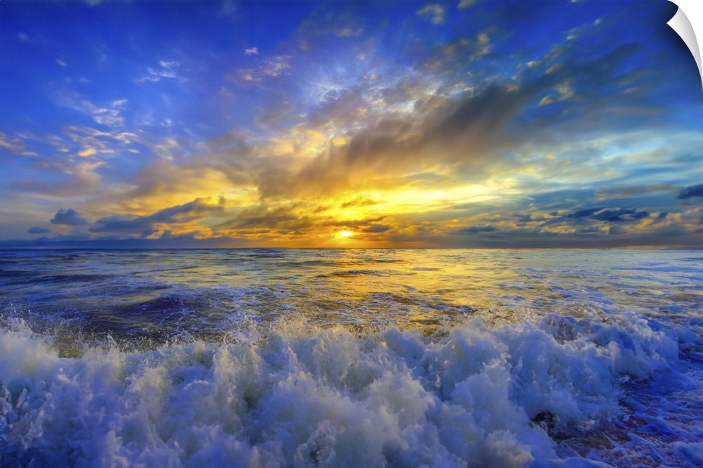 A brilliant gold and blue sunset over crashing ocean waves.