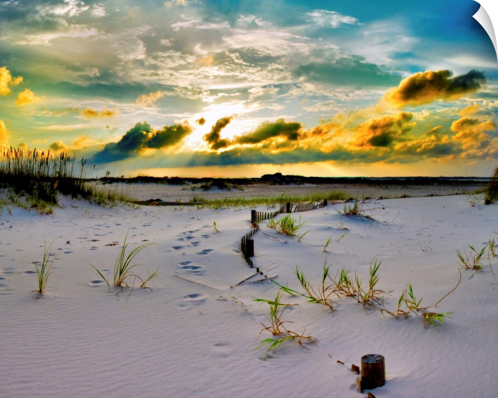 A golden sunset over a sandy pathway through the dunes down to the beach. Landscape taken near Pensacola Beach, Florida.