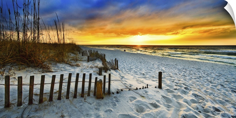 White sandy shore in a panoramic landscape with a burning red sunset sky. Landscape taken on Navarre Beach, Florida.
