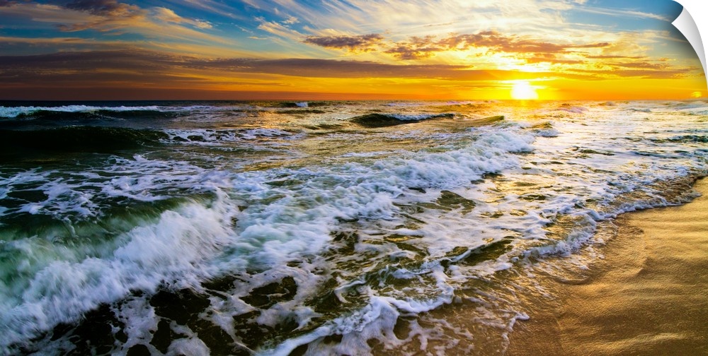 A panoramic landscape featuring a beautiful sunset over the sea. Golden light hits the crashing waves during the early mor...