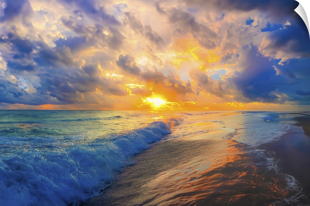 Soft heavenly white and pink clouds hover above a blue turquoise ocean. Waves break onto the beach.