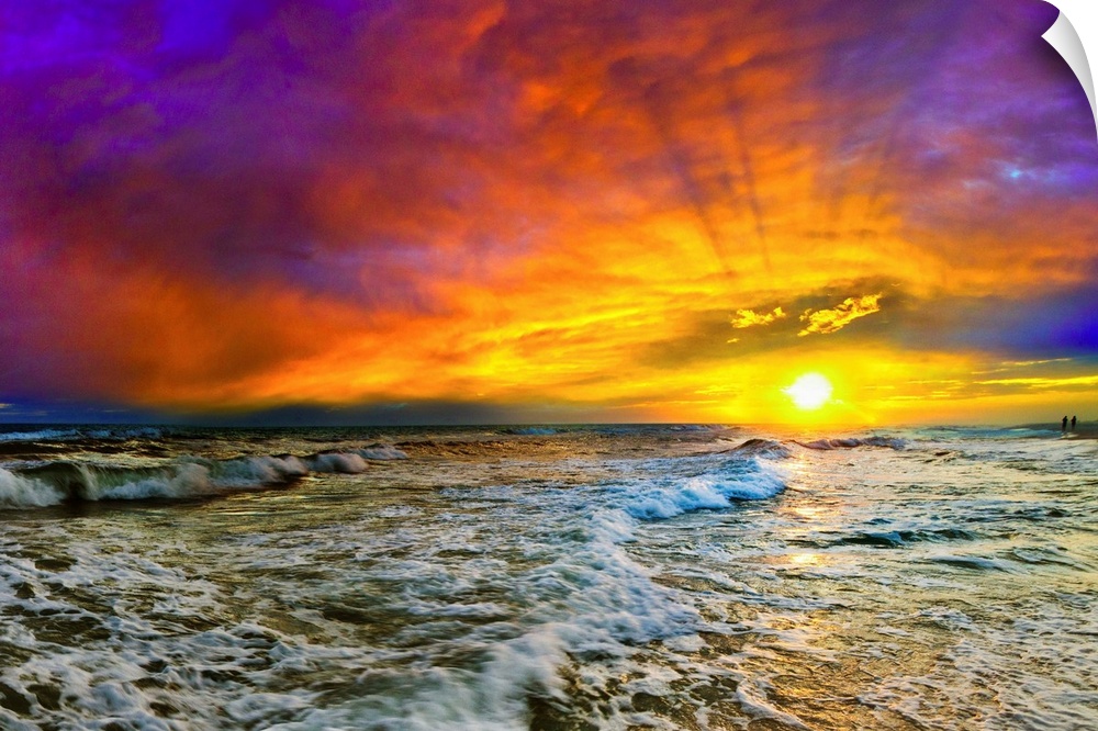 A beautiful purple, blue, and red sunset with shooting sun rays over the ocean. The yellow sun casts a sun trail and the sea.