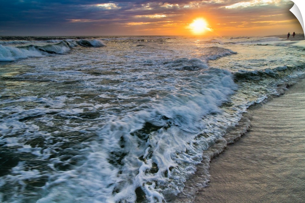 A sunset with crashing waves on the shoreline.