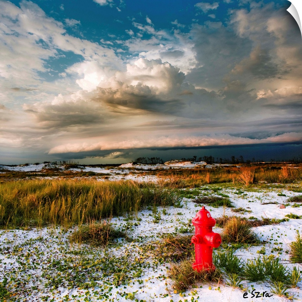 A red hydrant a midst a desert landscape with storm clouds overhead.