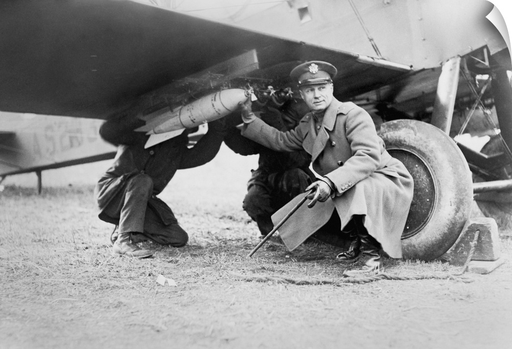 Brigadier General Billy Mitchell and another man, attaching a bomb under wing of airplane. Ca. 1925. He advocated military...