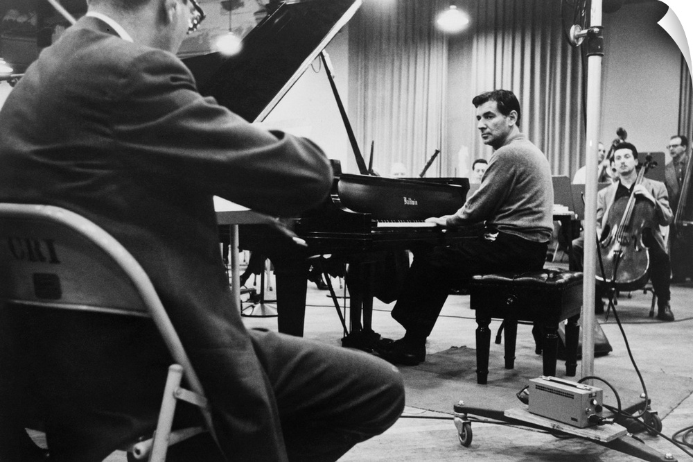 Leonard Bernstein, playing piano, amidst other musicians during a rehearsal in 1958.