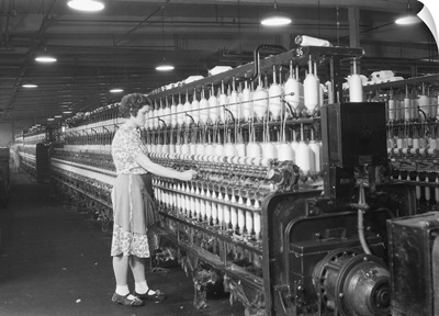 Woman standing at long row of bobbins, at a textile factory, Millville, NJ, 1936