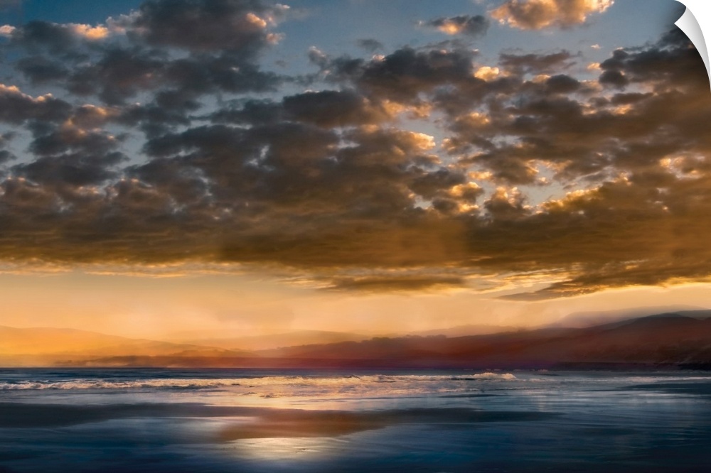 Seascape photograph with mountains in the distance and a cloudy sky at sunset.