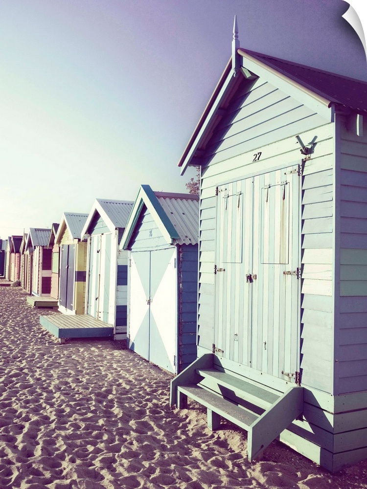 Slightly faded photograph of a row of colorful beach cottages right on the sand.
