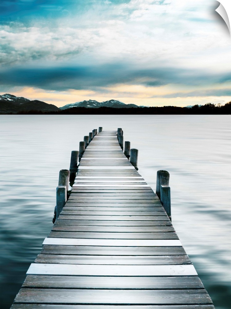 Photograph of a wooden boardwalk on a jetty with snow capped mountains in the distance.