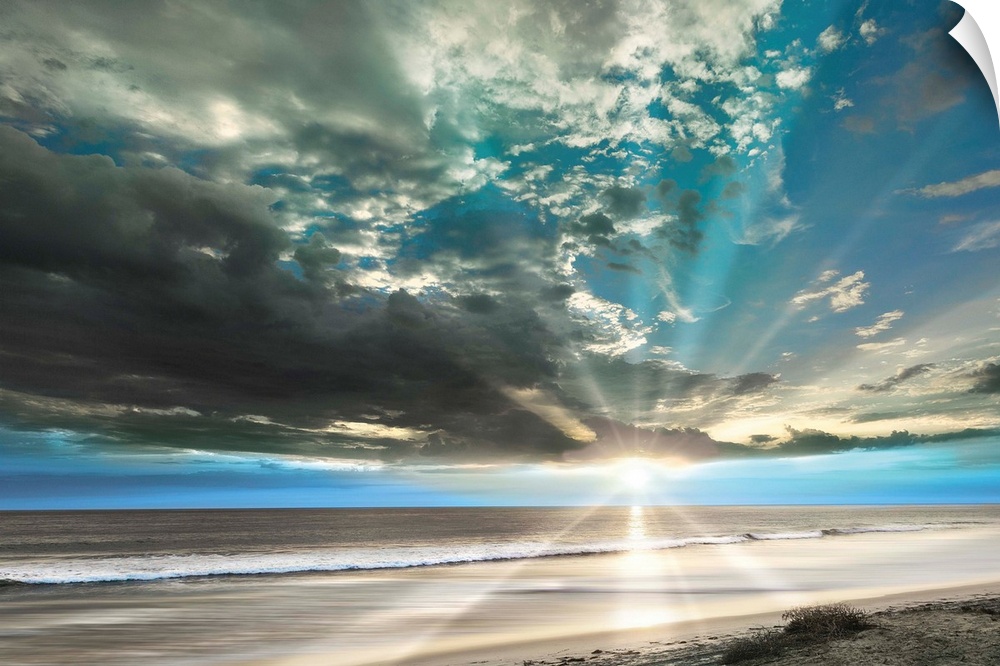 Stunning landscape photograph of the sun beaming over an empty beach with contrasting clouds in the sky.