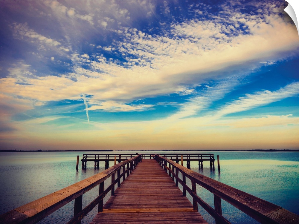 Photograph of a pier at sunrise with beautiful clouds.