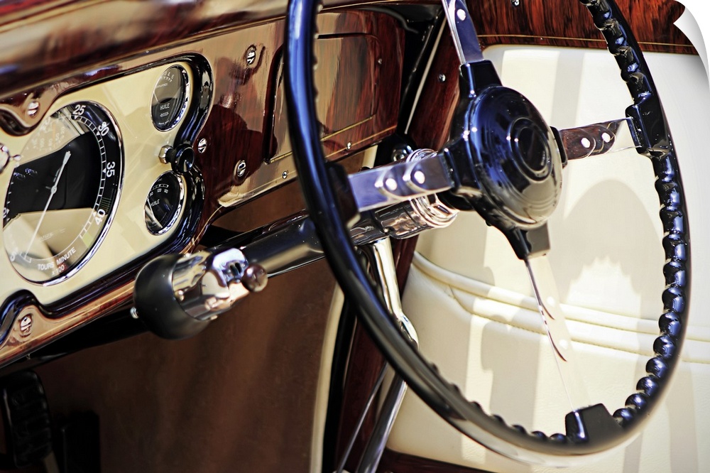 Large, landscape, close up photograph of the dashboard of a classic car, polished and shining, including the steering colu...