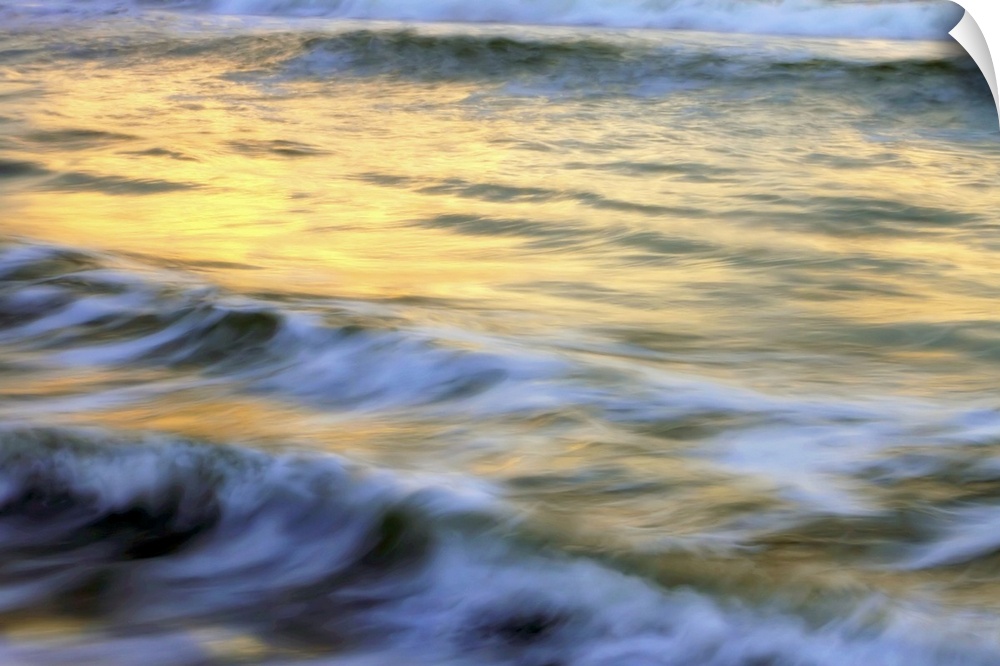Soft photograph of a sunset reflecting light on the ocean waves.