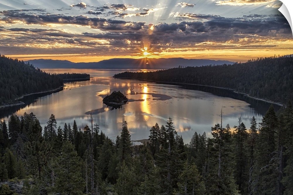 Landscape photograph of a beautiful sunset beaming through the clouds over Emerald Bay in California.