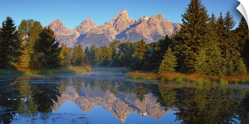 View of the Grand Teton Mountain range in Wyoming, reflected in a lake.